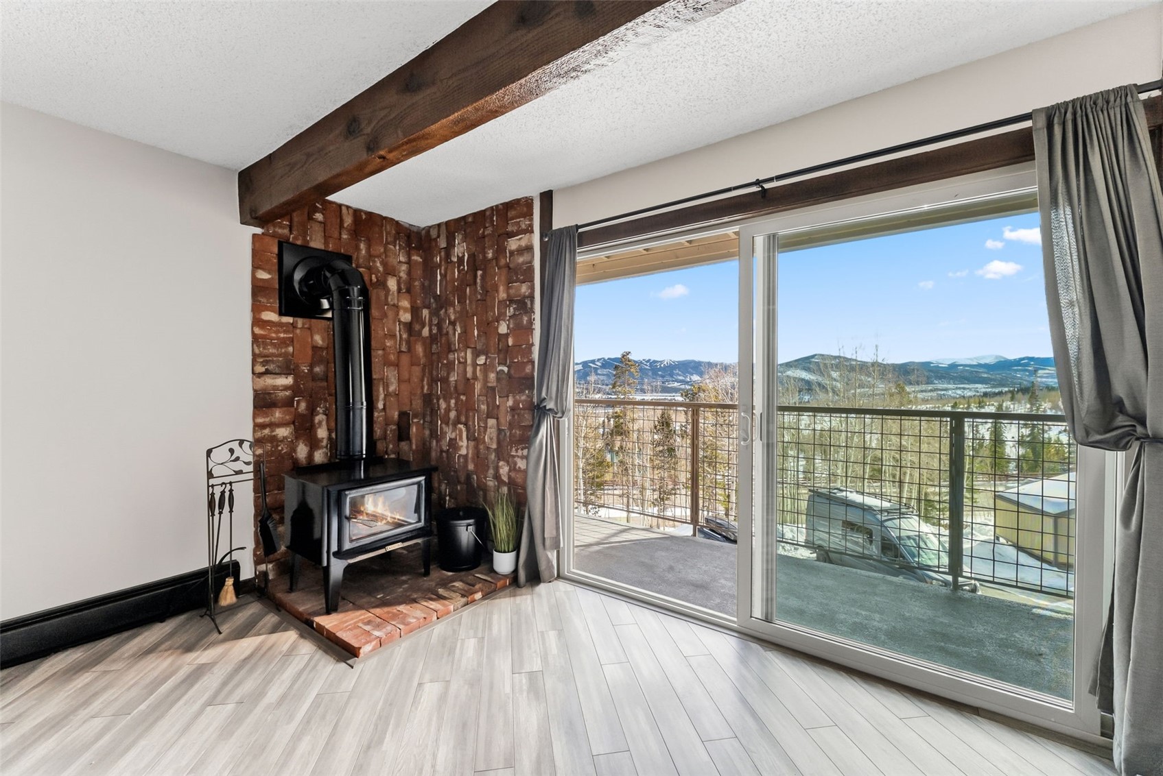 7124 Ryan Gulch Road, Unit 204 Wildernest, CO 80498 - Photo 9 of 36 Unfurnished living room with a mountain view, beam ceiling, a wood stove, light wood-type flooring, and a textured ceiling