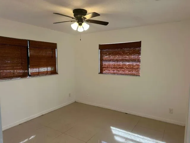 an empty room with a ceiling fan and a window