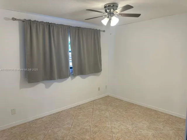 a view of an empty room with chandelier fan
