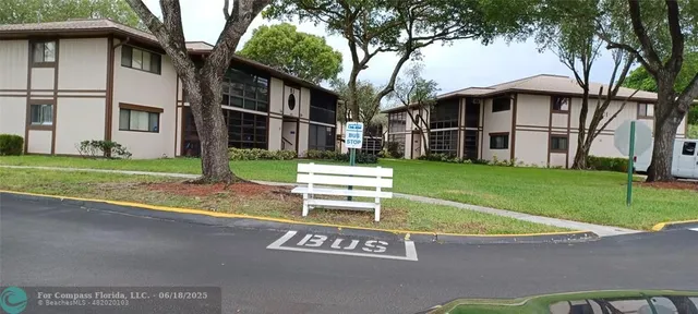 a view of a white house next to a yard with big trees