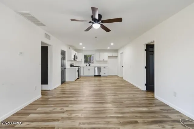 a view of empty room with wooden floor and ceiling fan