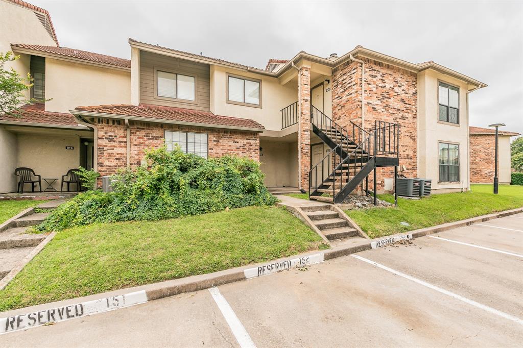 View of property with uncovered parking, stairs, stucco siding, and a front yard