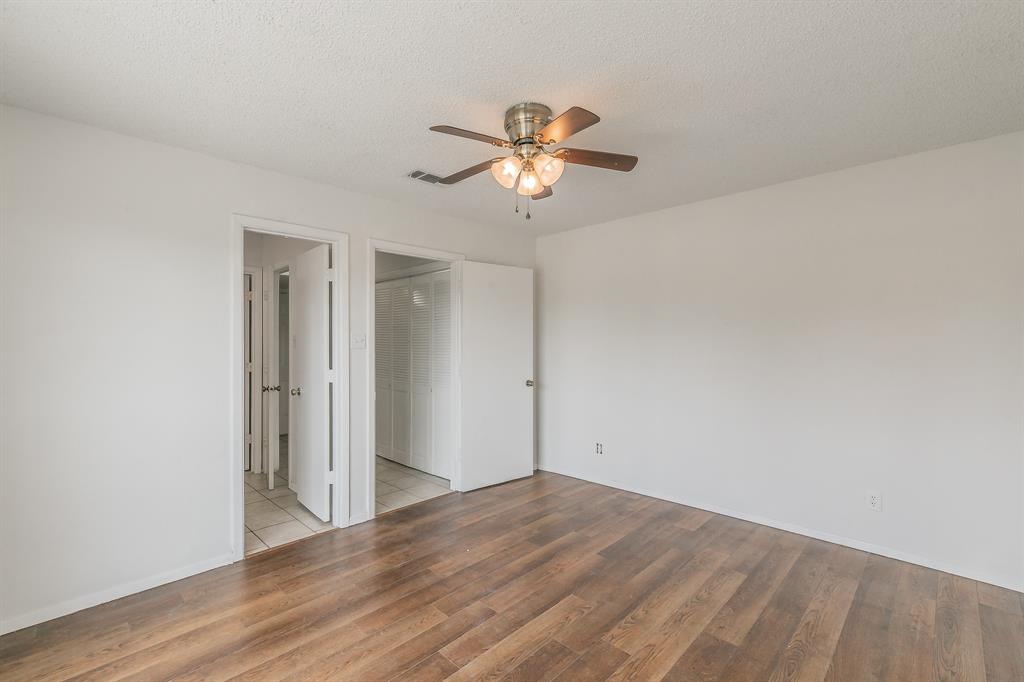 920 Turtle Cove, Unit 252 Irving, TX 75060 - Photo 16 of 34 Unfurnished bedroom featuring wood finished floors, a textured ceiling, ensuite bath, baseboards, and ceiling fan