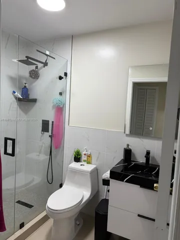 a white toilet sitting next to a bathroom sink and a shower