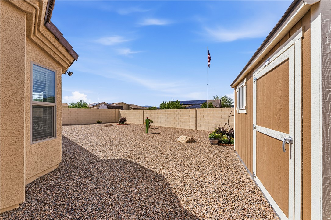 4143 North Stampede Road Kingman, AZ 86401 - Photo 42 of 42 Spacious gravel yard featuring a privacy block wall and a detached storage shed with a window