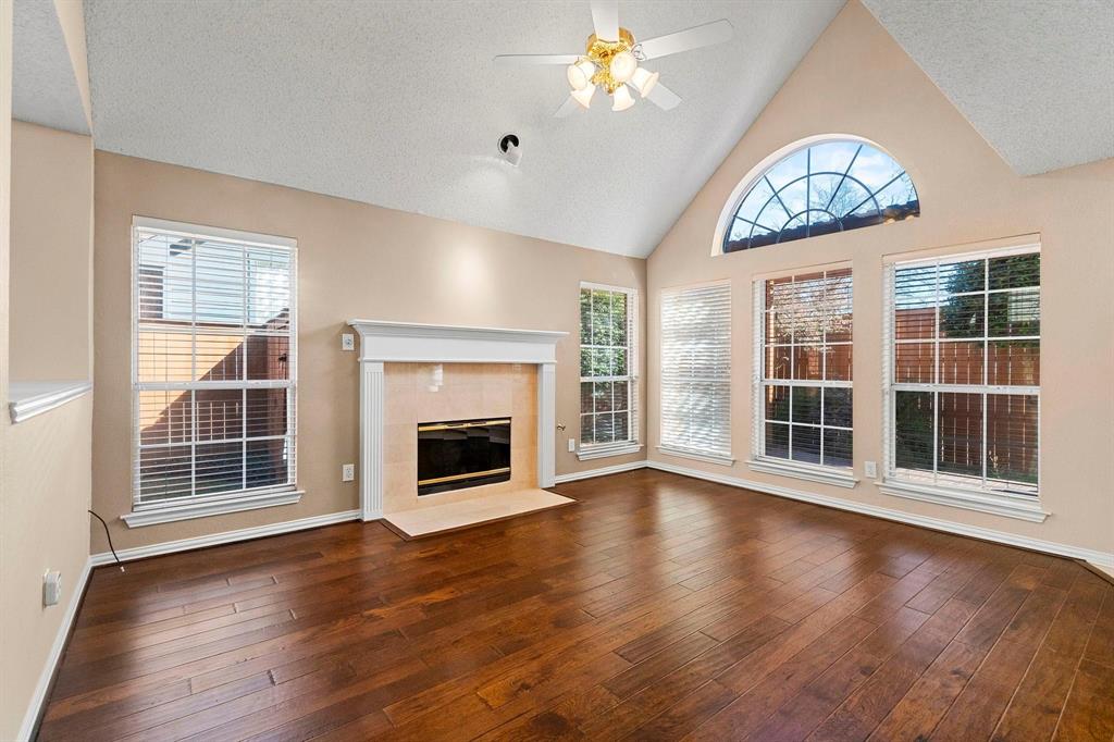 14588 Poe Court Addison, TX 75001 - Photo 9 of 28 an empty room with wooden floor fireplace and windows