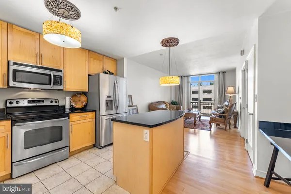 a kitchen with stainless steel appliances a stove a sink dishwasher a refrigerator cabinets and a dining table with wooden floor