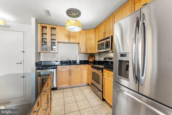a kitchen with stainless steel appliances granite countertop a refrigerator a stove and a sink