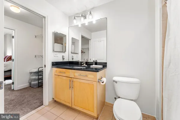a bathroom with a granite countertop toilet sink and mirror