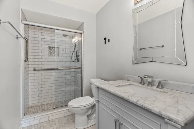 a bathroom with a granite countertop sink toilet and shower