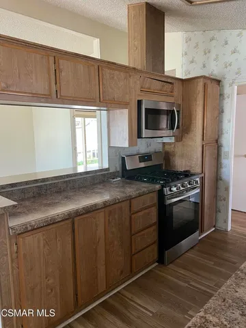 a kitchen with stainless steel appliances granite countertop a stove a sink and a microwave
