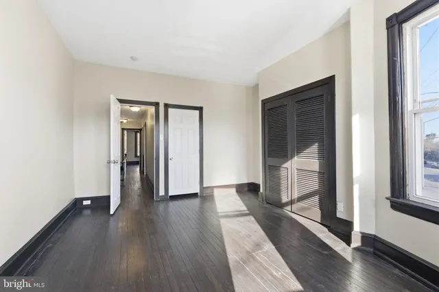 an empty room with wooden floor and windows