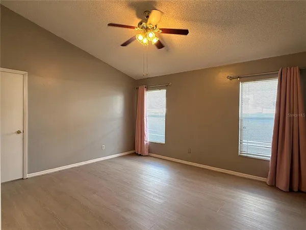 a view of empty room with wooden floor and fan