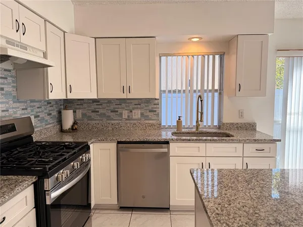 a kitchen with granite countertop a stove a sink and a refrigerator