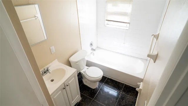a white toilet sitting next to a bathroom sink and a vanity