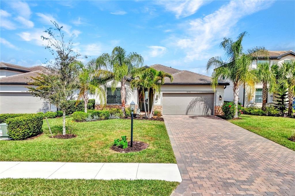 Ranch-style home featuring decorative driveway, a garage, a front lawn, a tile roof, and stucco siding