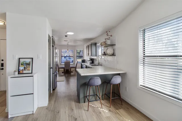 a kitchen with stainless steel appliances granite countertop a refrigerator a sink a stove and white cabinets with wooden floor