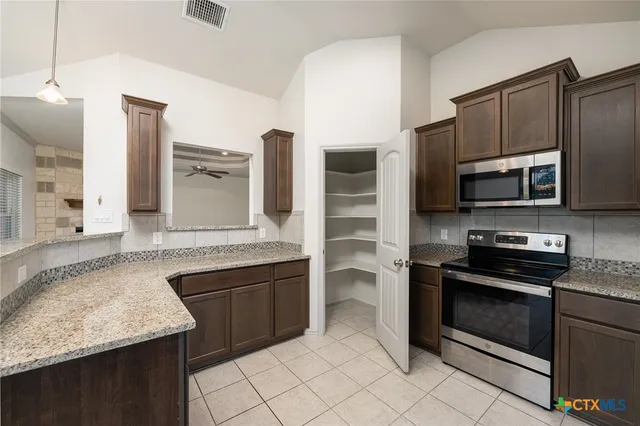 a kitchen with stainless steel appliances granite countertop a stove microwave and refrigerator