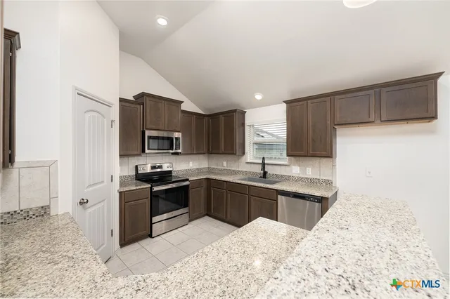 a kitchen with stainless steel appliances kitchen island granite countertop a sink and a stove