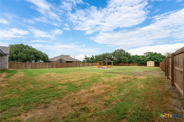 a view of a green field with wooden fence