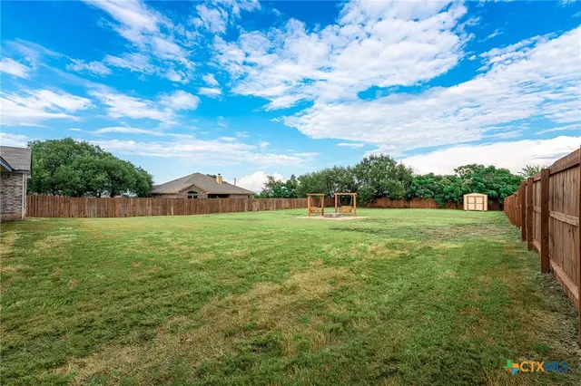 a view of a green field with wooden fence