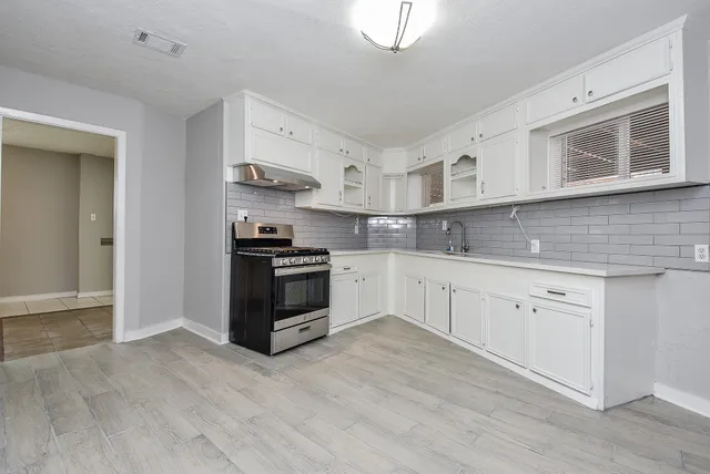 a kitchen with granite countertop white cabinets and stainless steel appliances