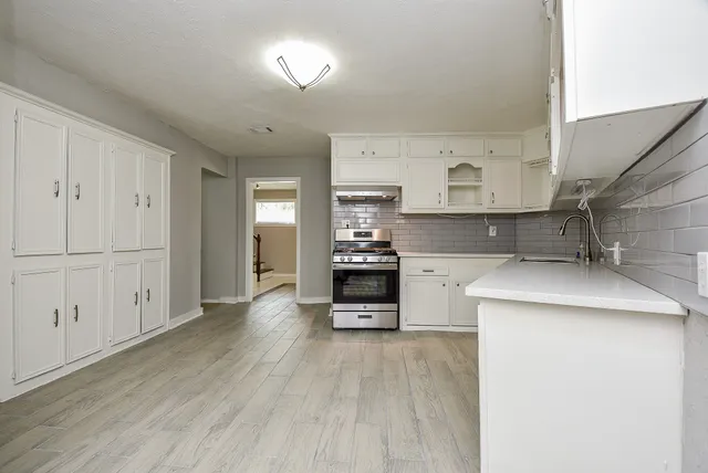 a kitchen with stainless steel appliances kitchen island wooden floors and white cabinets
