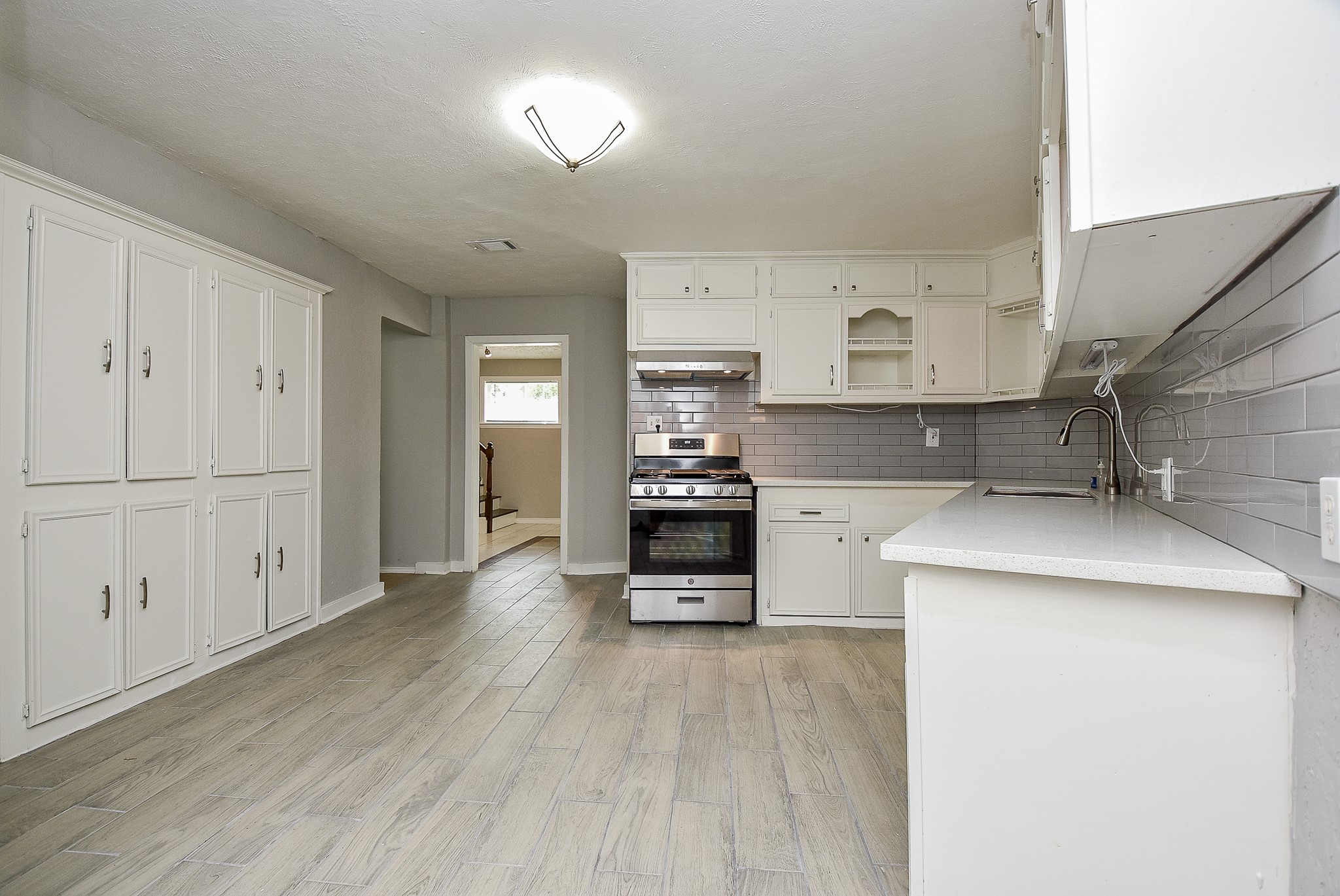 2509 Oakcliff Street Houston, TX 77023 - Photo 14 of 31 a kitchen with stainless steel appliances kitchen island wooden floors and white cabinets