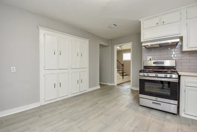 a view of kitchen and empty room with wooden floor