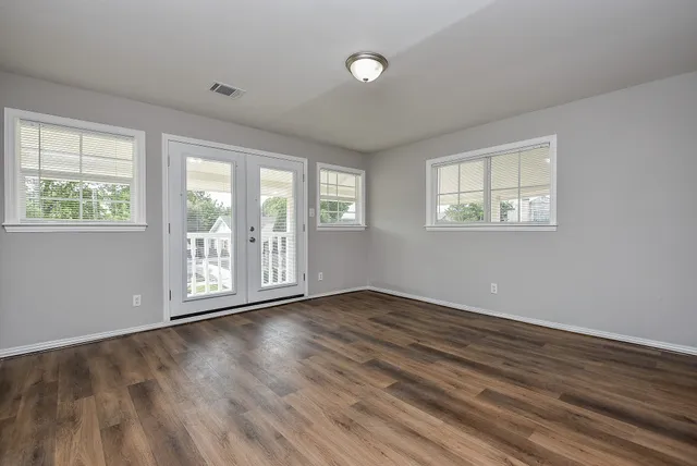 a view of an empty room with wooden floor and a window