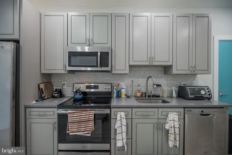 a kitchen with stainless steel appliances granite countertop a stove a sink and a white cabinets