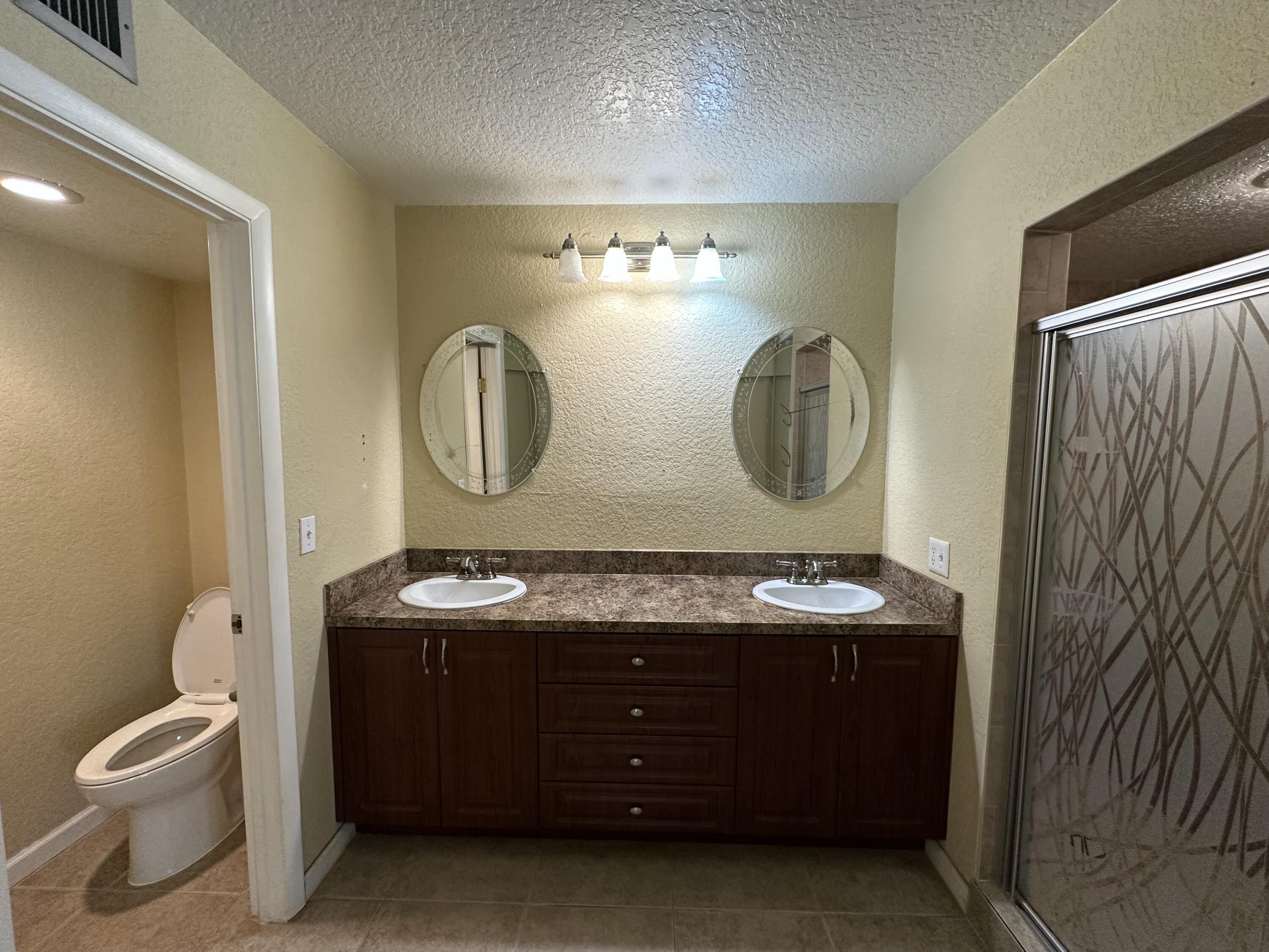 622 Springdale Circle Palm Springs, FL 33461 - Photo 13 of 13 a bathroom with a granite countertop toilet sink and mirror