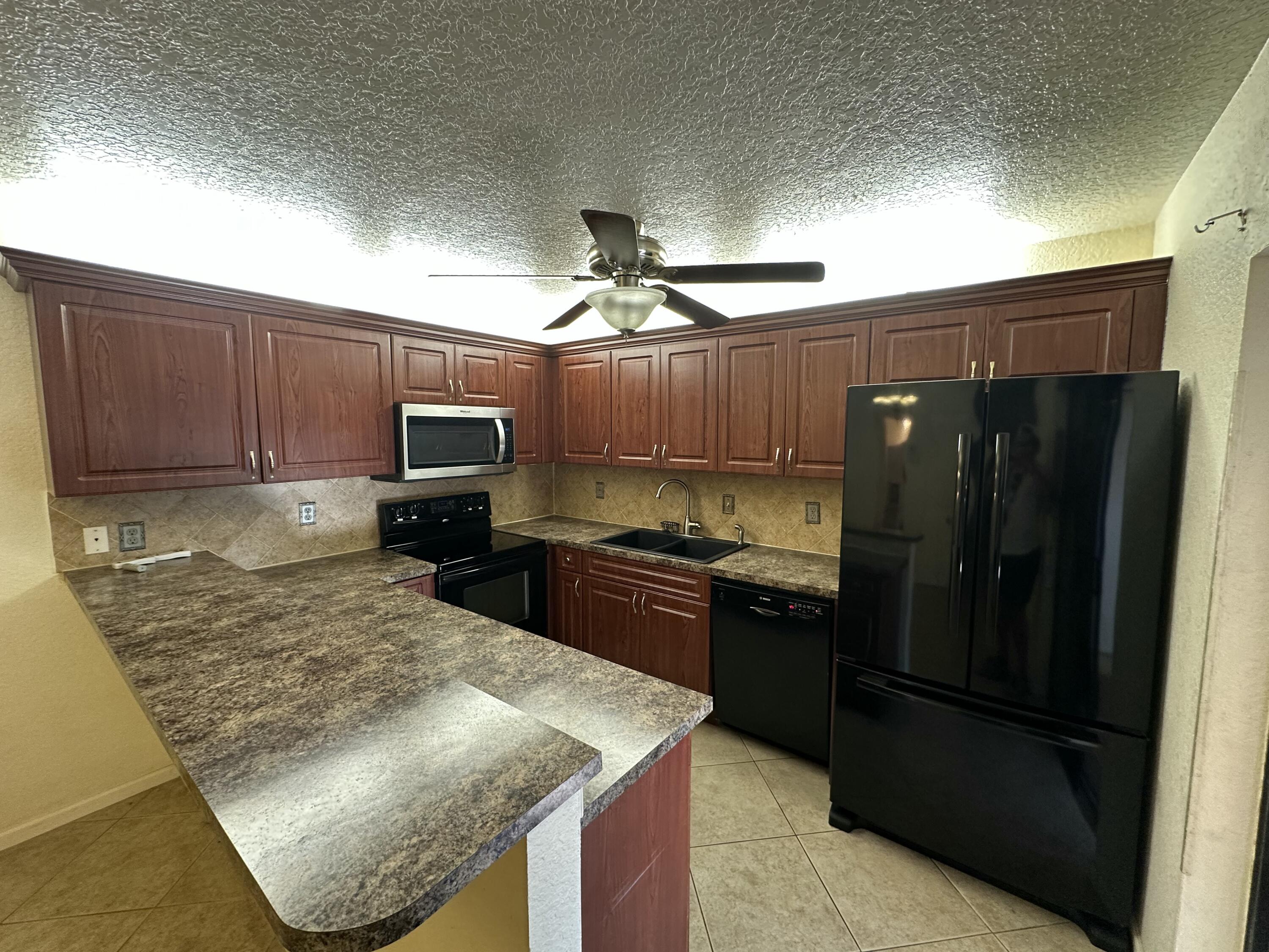 622 Springdale Circle Palm Springs, FL 33461 - Photo 8 of 13 a kitchen with a refrigerator sink and cabinets