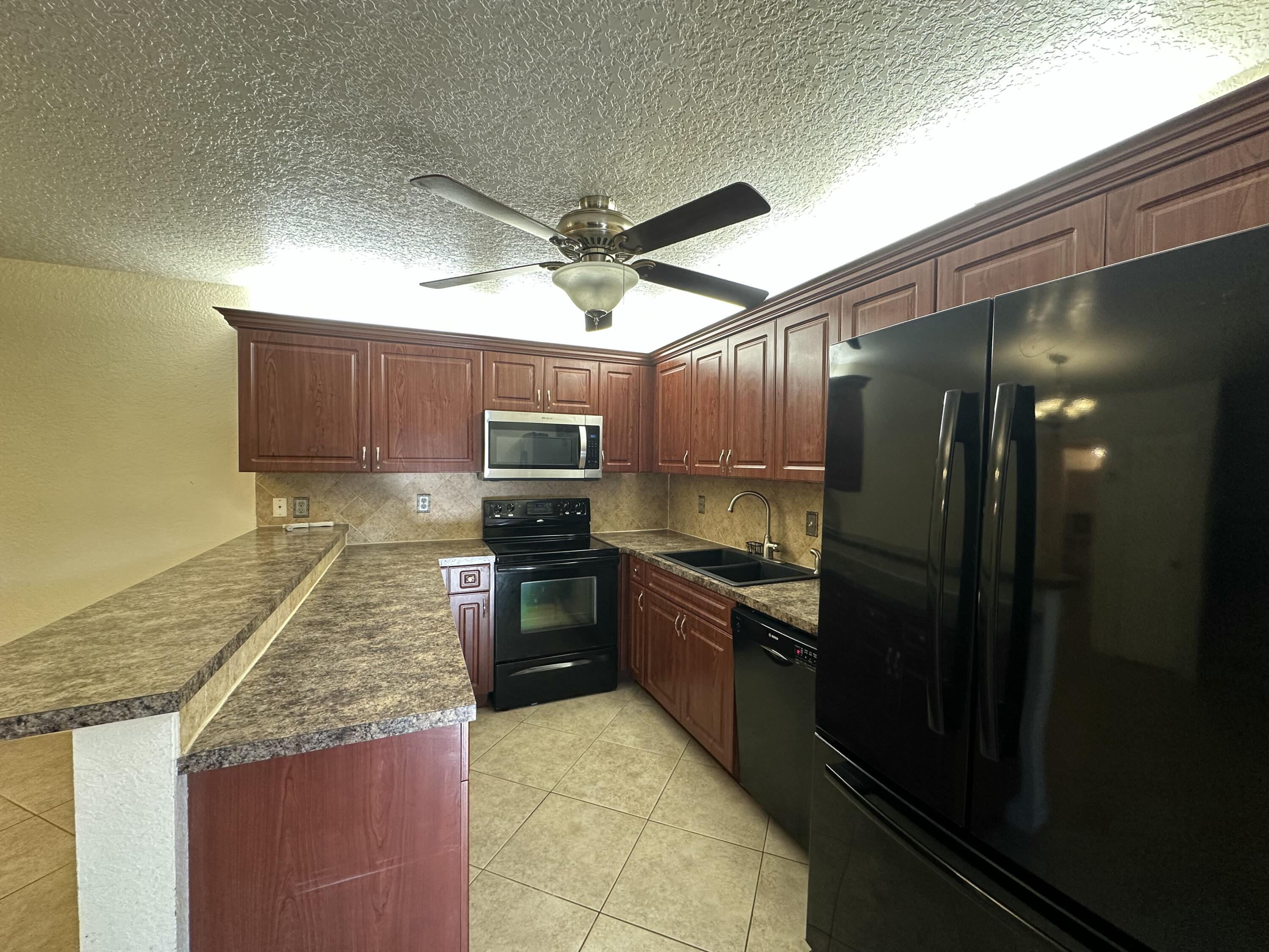 622 Springdale Circle Palm Springs, FL 33461 - Photo 9 of 13 a kitchen with granite countertop stainless steel appliances and wooden cabinets