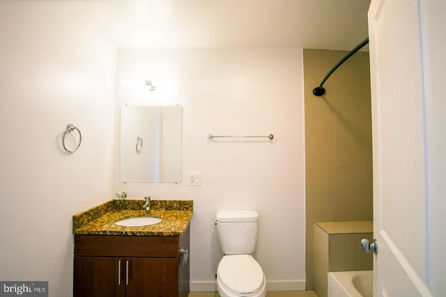 a bathroom with a granite countertop sink toilet and shower