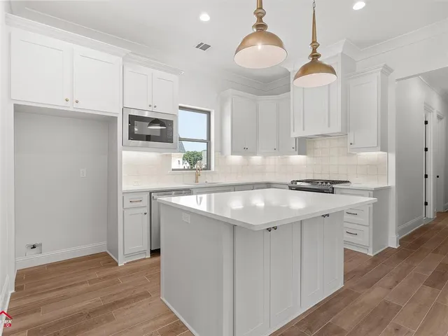 a kitchen with stainless steel appliances granite countertop a sink a stove a refrigerator and island with wooden floor