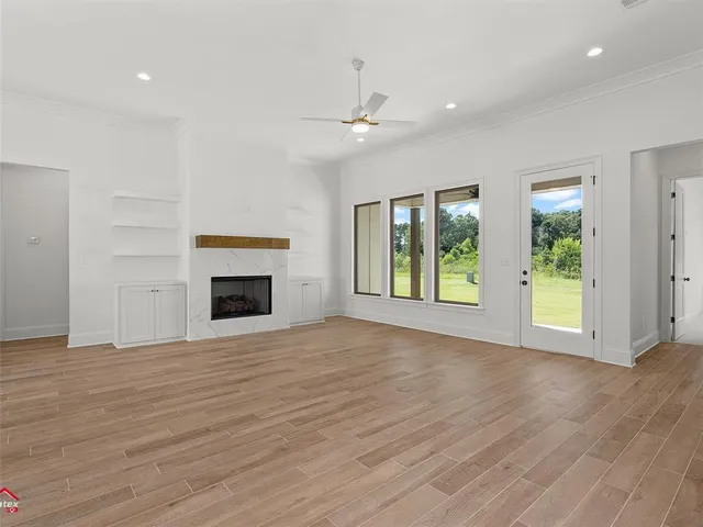 an empty room with wooden floor fireplace and windows