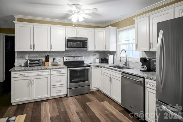 a kitchen with white cabinets stainless steel appliances and a window