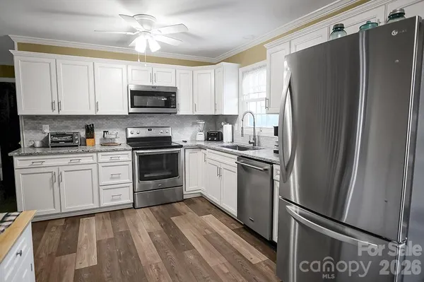 a kitchen with white cabinets stainless steel appliances and a window