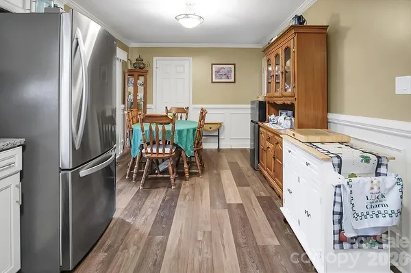 a kitchen with stainless steel appliances a refrigerator a stove a sink and a dining table with wooden floor