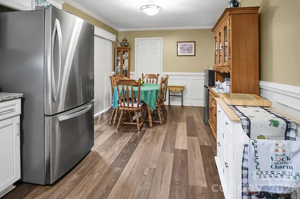 a kitchen with stainless steel appliances a refrigerator a stove a dining table and chairs with wooden floor