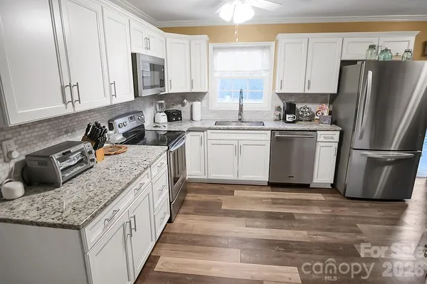 a kitchen with stainless steel appliances granite countertop a sink stove refrigerator and cabinets