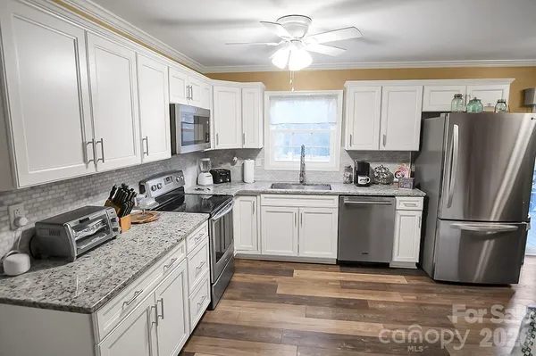 a kitchen with stainless steel appliances granite countertop a sink stove refrigerator and cabinets