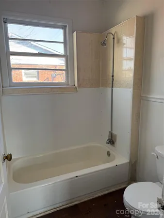 a bathroom with a bathtub toilet and window