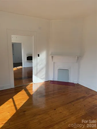 a view of empty room with wooden floor and fireplace