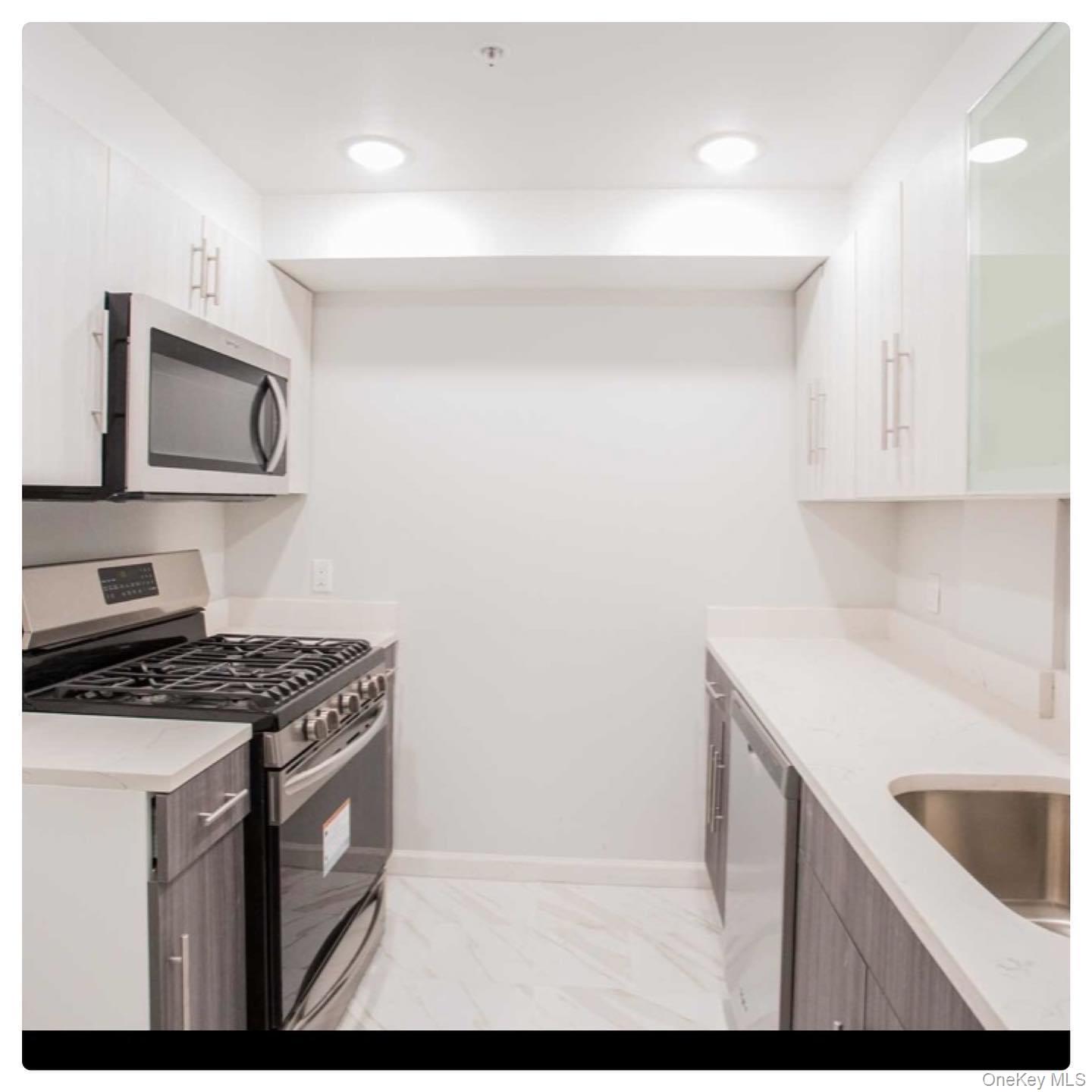 5 Grace Avenue, Unit 2J Great Neck, NY 11021 - Photo 7 of 15 a kitchen with a sink stove and microwave