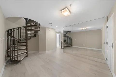 a view of an empty room with wooden floor and a bathroom