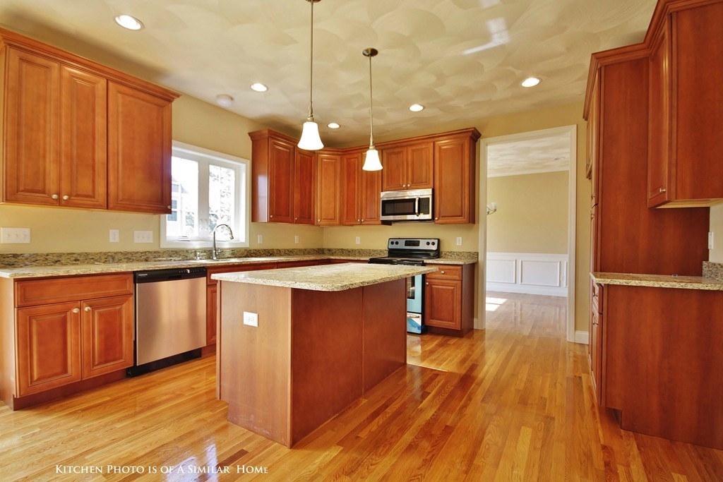 a kitchen with kitchen island granite countertop wooden floors stainless steel appliances a sink and a window