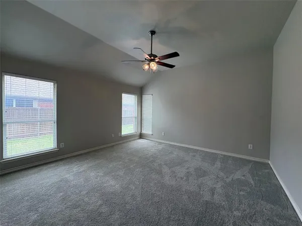 an empty room with windows and fan