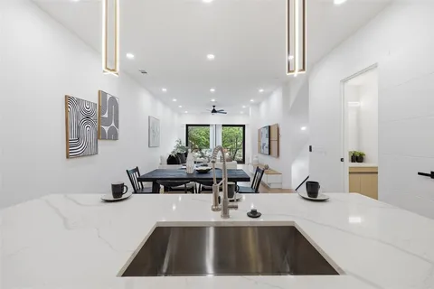 a view of a kitchen with kitchen island stainless steel appliances a sink a counter top space and living room view